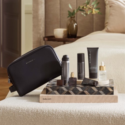 Beauty products and bags are arranged on a decorative tray in a cozy bedroom.