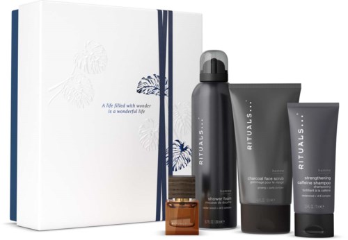 Geschenkset mit weißer Verpackung, blauer Schleife und Rituals-Hautpflegeprodukten, darunter Duschschaum, Aktivkohle-Gesichtsmaske und stärksames Koffein-Shampoo.