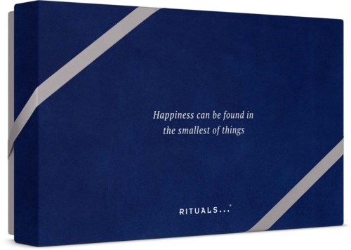 En mörkblå låda med vita diagonala linjer och texten Happiness can be found in the smallest of things. RITUALS.