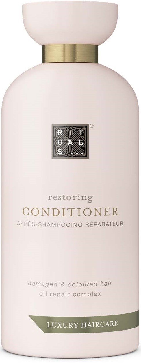 A white bottle labeled 'Restoring Conditioner' for damaged, colored hair with oil repair, part of luxury haircare.