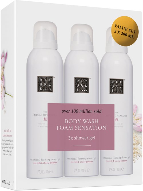 Tre vita flaskor med skum shower gel med blommarmönster på förpackningen och en rosa etikett, i en låda.