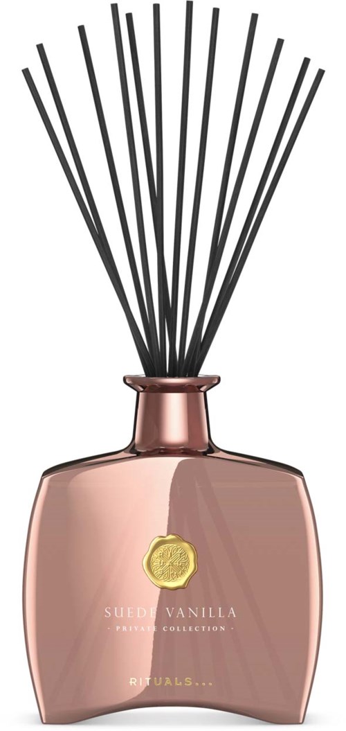 Eine rosa Parfümflasche mit schwarzen Räucherstäbchen und einem goldenen Etikett vorne.
