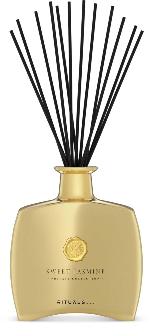 Eine goldene Diffusorflasche mit schwarzen Stäbchen und einem Etikett mit 'Sweet Jasmine'.