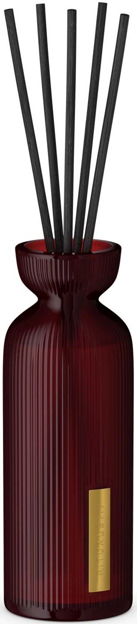 Eine lange, rote, gerippte Vase mit schwarzen Stäbchen darin vor einem schwarzen Hintergrund.