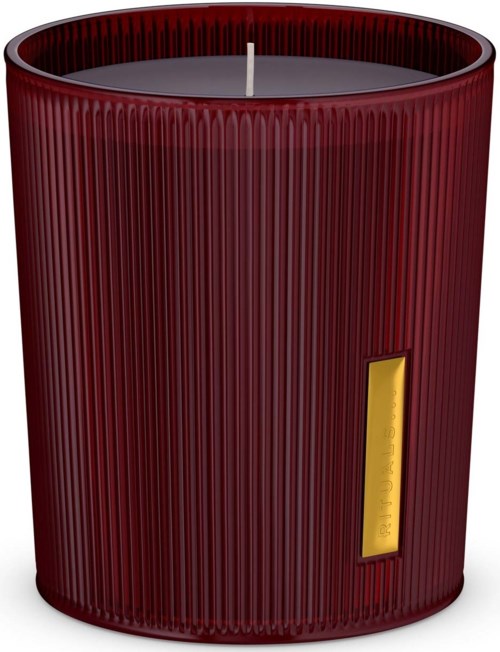 Ein langer, roter, geriffelter Duftkerze mit einem kleinen Docht oben und einem gelben Etikett an der Seite.