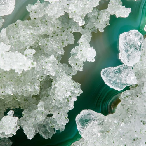 Zbliżenie na kryształowe cząsteczki soli i szorstkie kamienie mineralne, z mieszanką białych i przezroczystych tekstur.