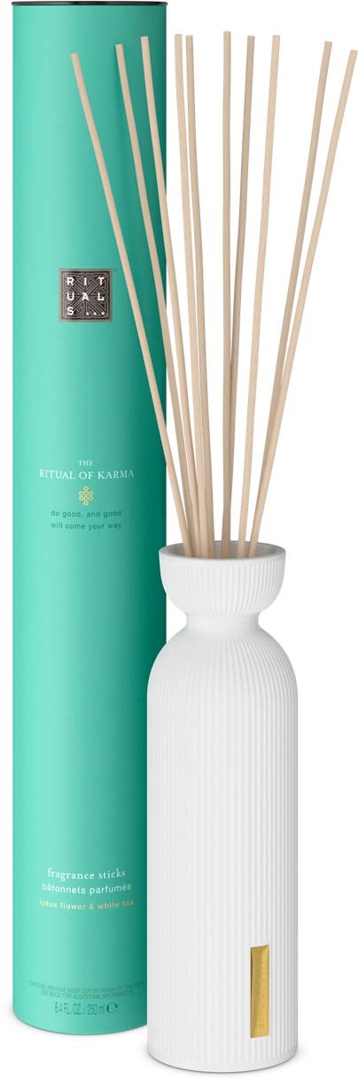 Eine weiße Keramik-Diffuser-Flasche mit Reeds, neben einer langen türkisen Box mit schwarzem Etikett.