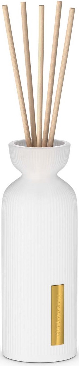 Eine weiße, hohe Vase mit einem goldenen Etikett, die mehrere Holzzweige hält.