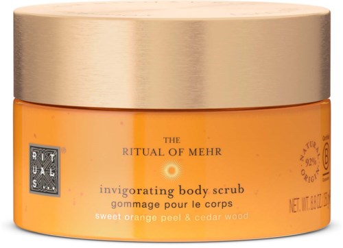 A jar of body scrub with a gold lid and orange content, labeled as invigoration with orange peel and cedar wood.