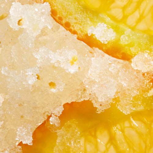 A close-up of a yellow lemon slice with salt crystals on its surface.