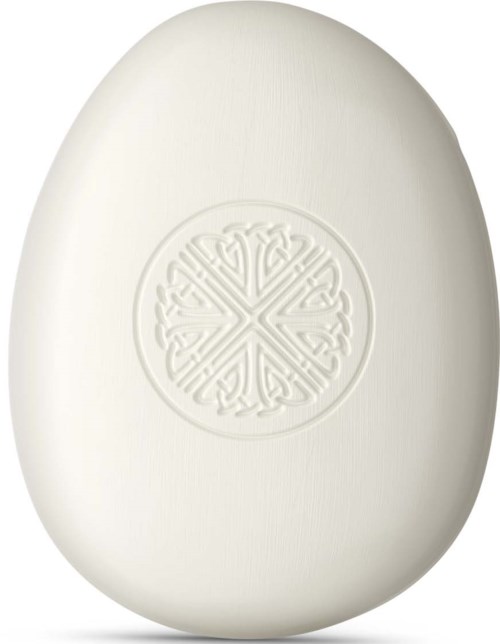 A smooth white oval soap with a decorative embossed design in the center.