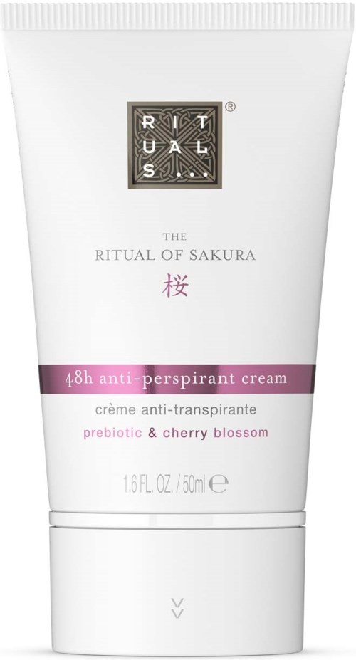 En hvit tube med deodorantkrem med lilla etikett, svart og hvitt merke, og rosa kirsebærblomst symbol.