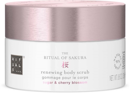 Ein zylindrischer Behälter für ein Körperpeeling mit einem roséfarbenen Silberdeckel, etiketti 'Ritual of Sakura' mit Kirschenblüte-Infos.