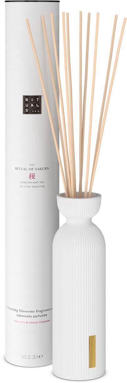 A white vase with sticks and a tall, round box labeled 'Ritual of Sakura'.