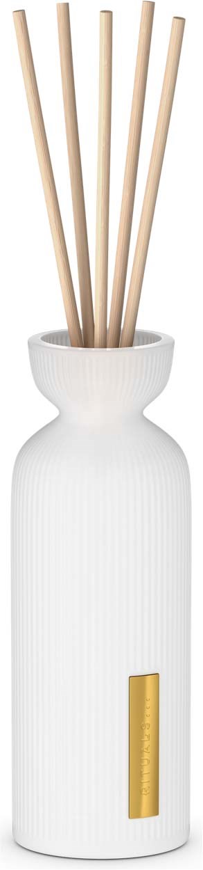 A white diffuser with five wooden sticks inside, standing on a black background.