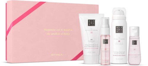 Sats med hudvårds- och kroppsvårdsprodukter i en rosa box, inklusive lotioner, duschgeléer och sprayar.