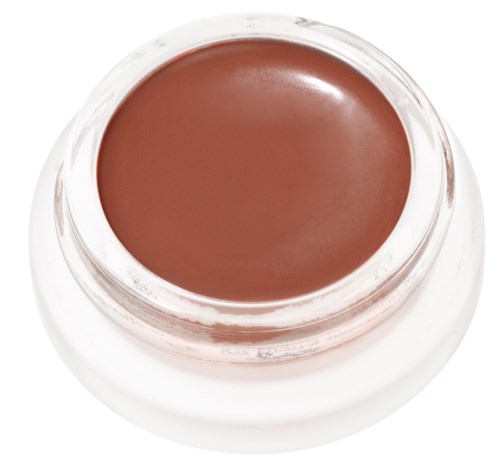 Ein kleiner runder Behälter enthält braune Creme oder Make-up, mit einer glänzenden Oberfläche. Es ist überwiegend weiß.