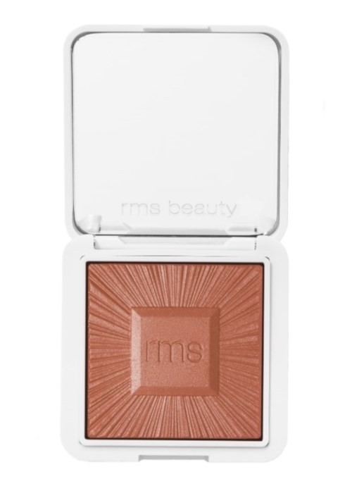 Ein Make-up-Produkt in einem offenen weißen Kompakt mit peachfarbenem Puder.
