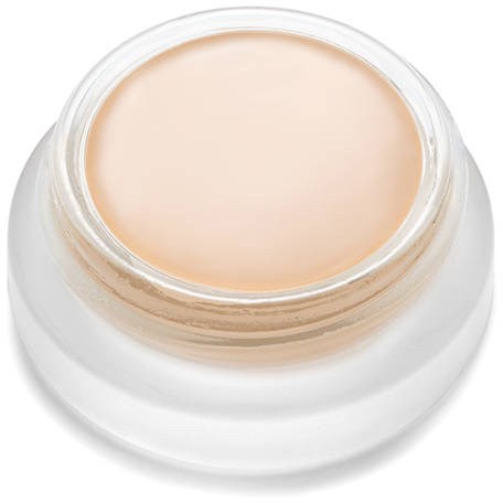 Ein kleiner Behälter mit beigefarbener Creme oder Make-up, von oben gesehen, mit weißer Basis.