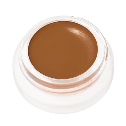 En liten burk med brunt krämer eller makeup, sett uppifrån, med ett vitt lock.