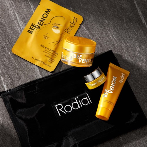 Skincare products include a face mask, cream, and a small jar, all in yellow packaging, with a Rodial travel bag.