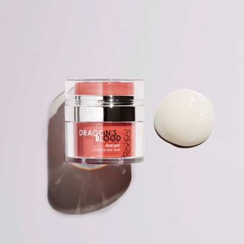 A small jar of pink eye gel labeled 'Dragon's Blood' with a white round object beside it.