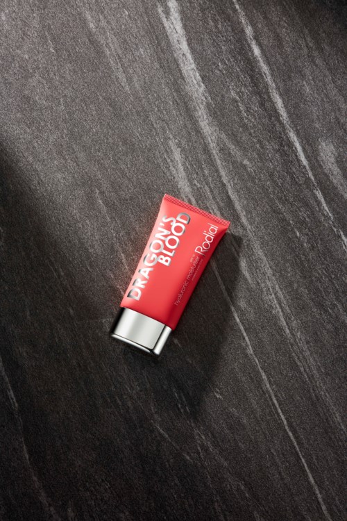 Rode tube met 'DRAMATIC BLOOD' ligt op donkergrijze ondergrond.