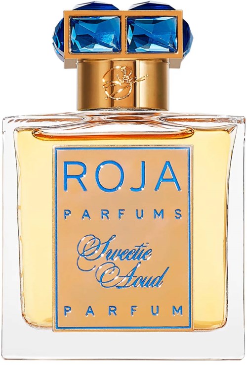 Ein Parfümflasche mit blauer und goldener Kappe, Etikett mit 'ROJA PARFUMS' und 'Sweetest Sand'.