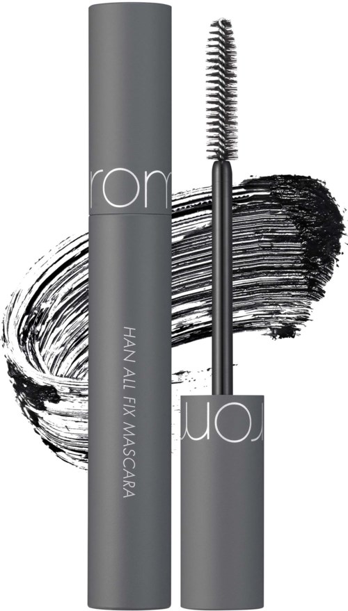Een mascara buis met een kwast, zwarte make-up vlek, en grijze verpakking met witte tekst.