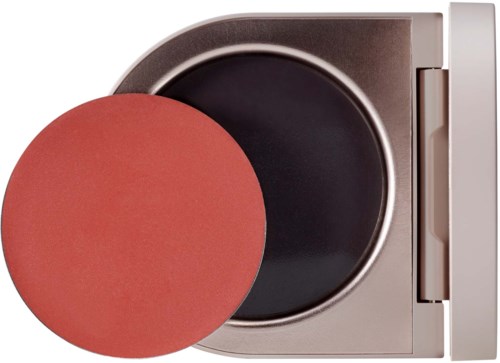 A compact, round, pink makeup sponge near a black circular surface in a small, rectangular, white container.