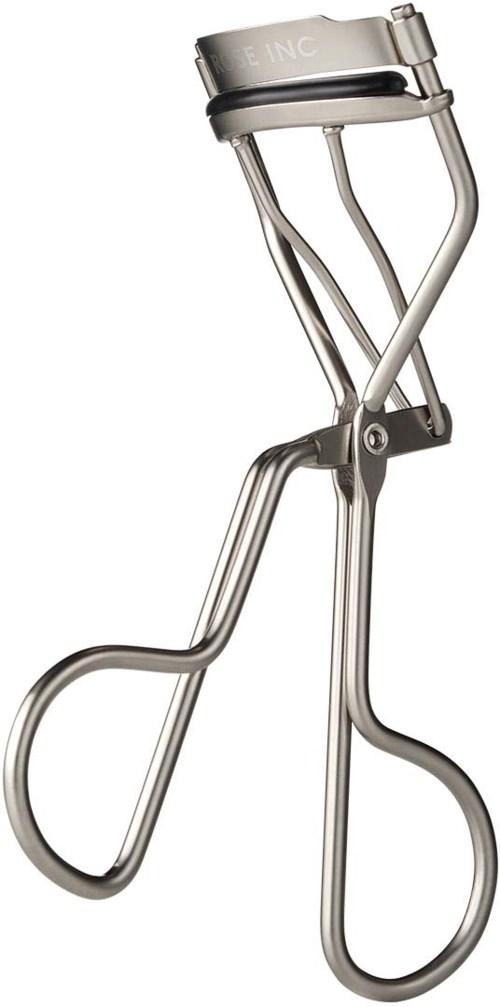 A metal eyelash curler with a handle, curved clamp, and a small pad for curling eyelashes.