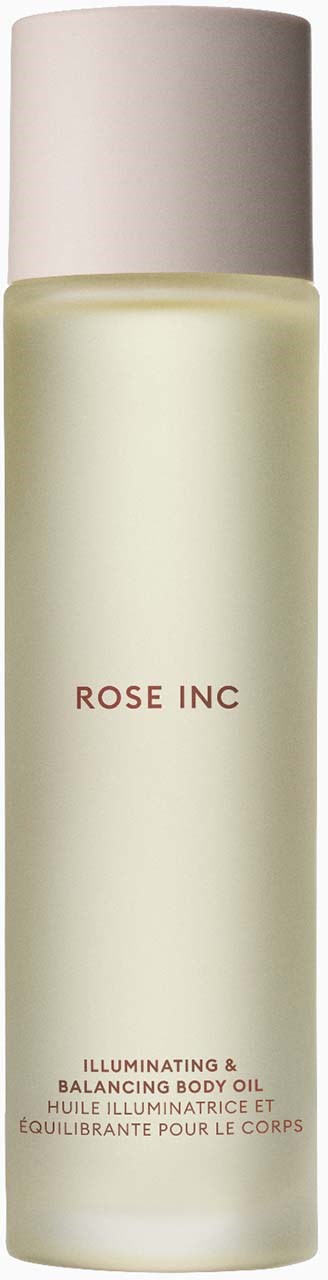 Pitkä, valkoinen pullo merkinnällä 'Rose Inc'. Se on valaistava ja tasapainottava vartaloöljy. Yksinkertainen muotoilu ja vaaleanpunainen teksti.