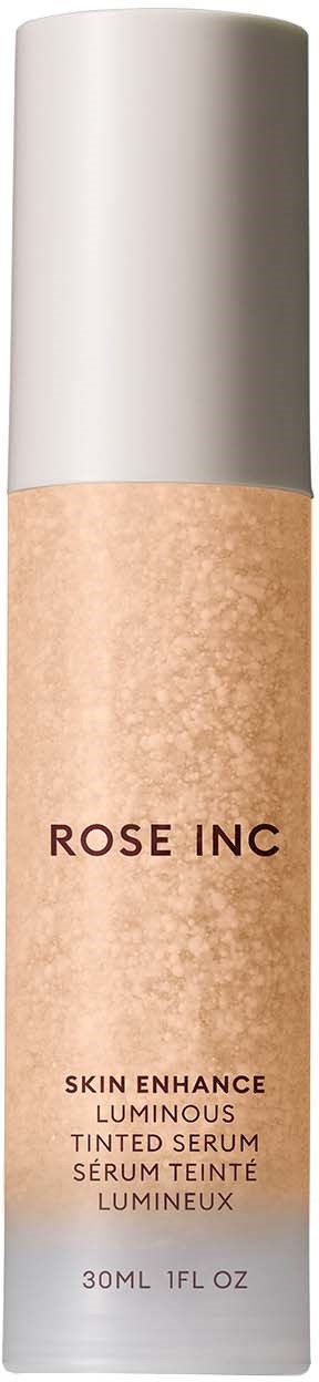 A tall, white bottle with a pink-beige label saying 'ROSE INC' and details about a skin serum.