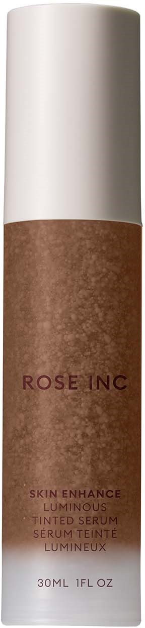 A brown tinted serum in a tall white bottle with a white cap, labeled 'ROSE INC' and 'SKIN ENHANCE LUMINOUS'.