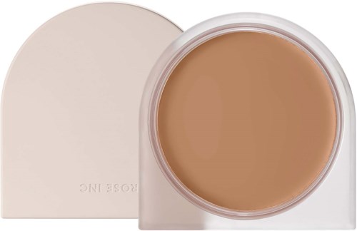 A jar of beige foundation with a white lid, partially open, showing the cream-like product inside.
