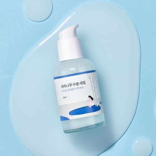 Eine Sprühflasche mit weißer Pumpe und koreanischem Etikett, auf blauem Hintergrund.
