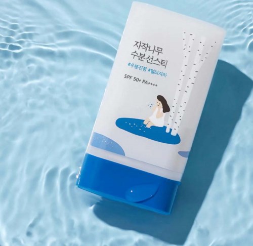 Een Koreese zonnebrandverpakking met een meisje dat water sproeit, geplaatst op een blauwe waterachtergrond.