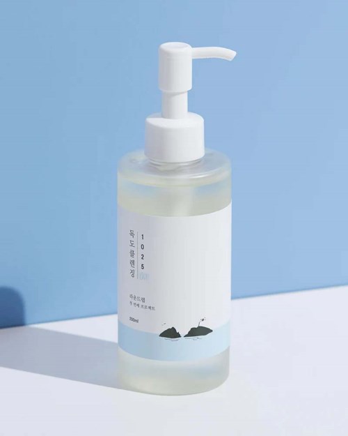 Eine klare Flasche mit weißer Pumpe steht vor einem hellblauen Hintergrund und enthält eine transparente Flüssigkeit.