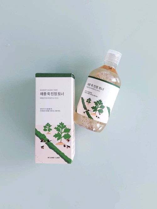 Eine Box und eine Flasche mit Etiketten, die grüne Pflanzen und kleine Tiere zeigen, vermutlich Kräuter- oder pflanzenbasierte Produkte.