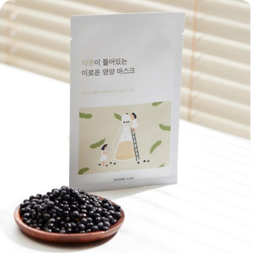 Ein Heft mit koreanischem Text und einer süßen Illustration, vor einer Schale mit kleinen schwarzen Beeren auf einer hellen Oberfläche.