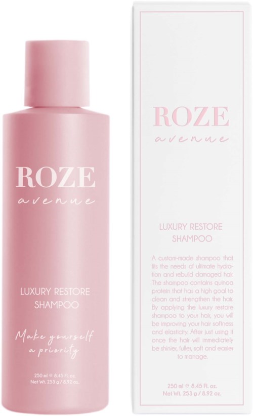 En rosa schampoflaska och en lång vit förpackning med rosa text. Etiketten säger 'ROZE avenue' och 'Luxury Restore Shampoo.'