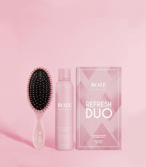 En hårborste, en rosa sprayflaska och en rosa box med etiketten 'ROZE Refresh DUO' på en rosa bakgrund.