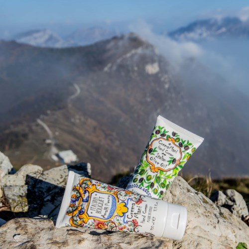 Two tubes of cream placed on rocks with mountain scenery in background.