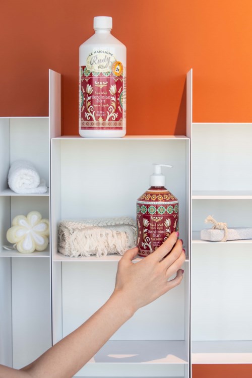 Two bottles of Shampoo and body wash are on a white shelf with items like towels and a sponge.