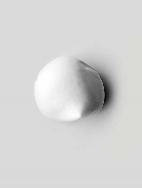 A smooth, white, round object with a slight shadow on a light grey background.