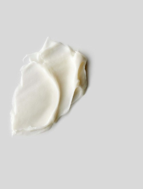 Tre vita, oregelbundna bitar av vad som verkar vara kräm eller smör på en enkel grå bakgrund.