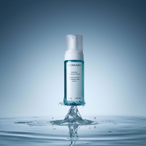 A clear bottle with blue label is falling into water, creating a splash and ripples.