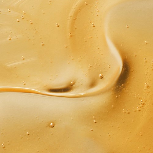 Gleiche, goldene und cremige Oberfläche mit kleinen Blasen und Wirbeln.
