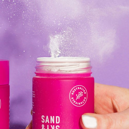 Pinkfarbener Behälter mit weißem Pulver, das herausfällt, und Staub in lila Hintergrund.