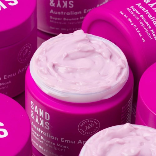 Pinkfarbene Gläser mit Creme, etiketti als australische Emu Apple Gesichtsmaske, werden in einer Gruppe gezeigt.